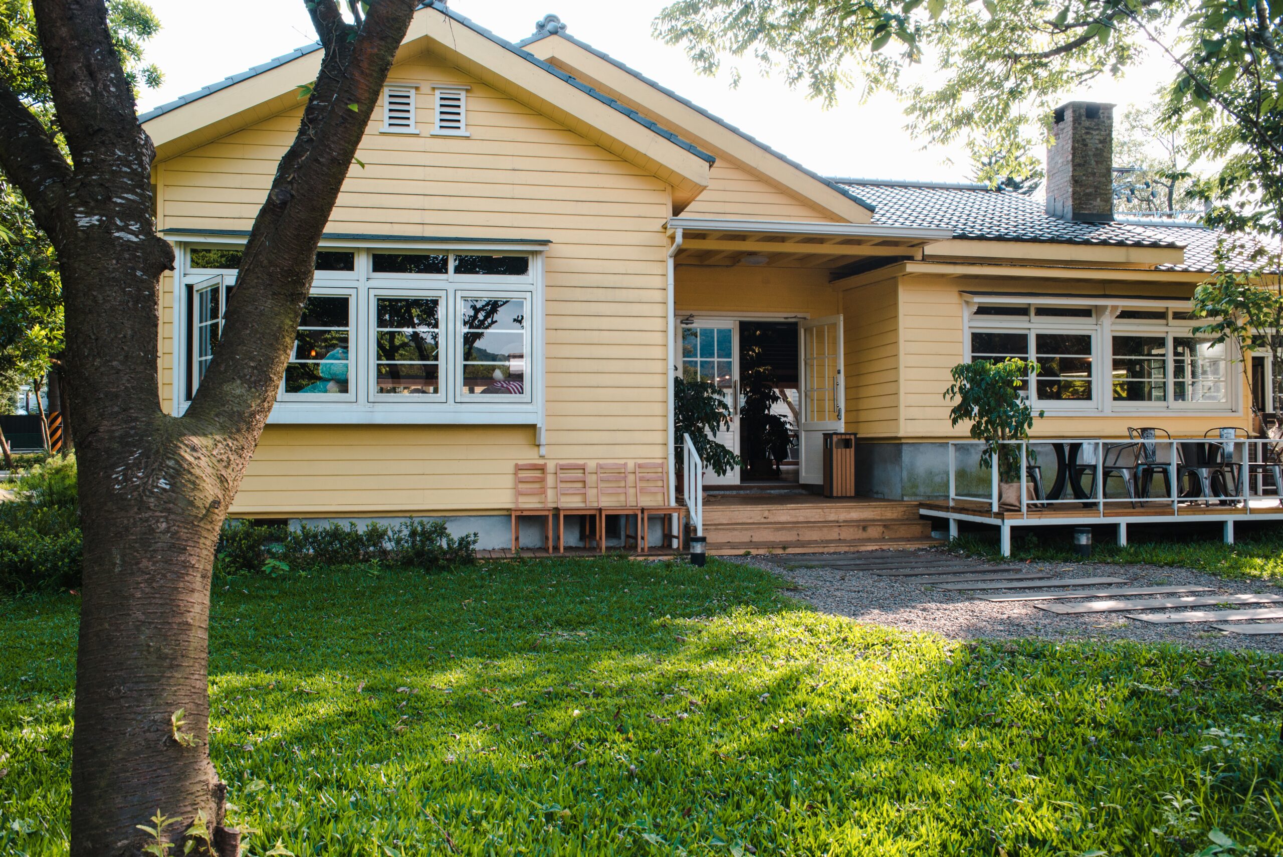 A charming yellow house with wooden windows and green grassy garden
